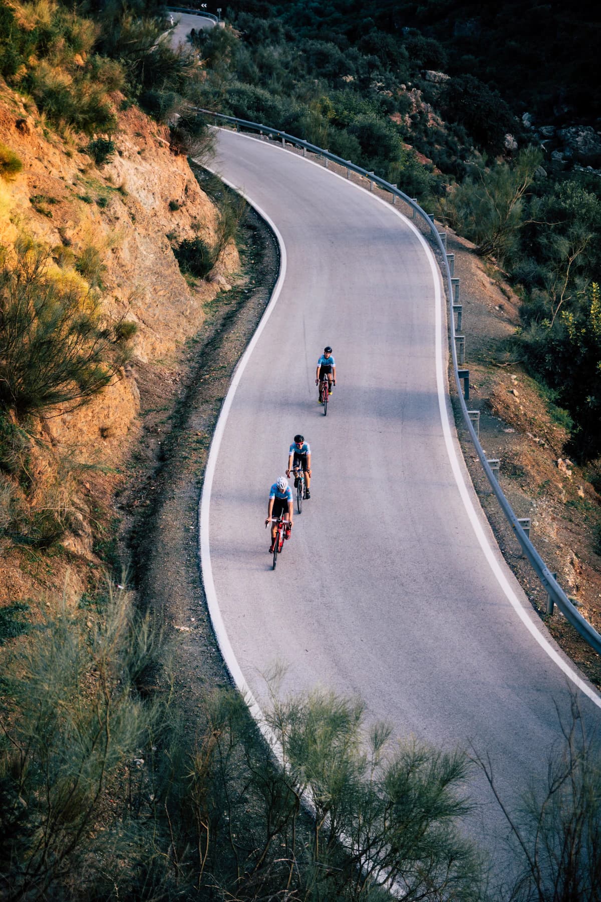Three cyclists riding on a scenic road during daytime